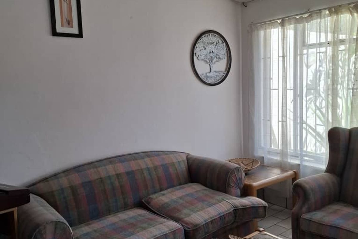 A dated hotel living area featuring tiled flooring, a drop ceiling, and security camera installation.