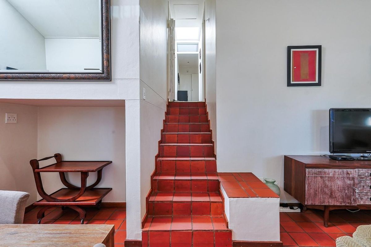 Living area featuring terracotta tiled flooring and a central staircase leading to an upper level with a skylight.