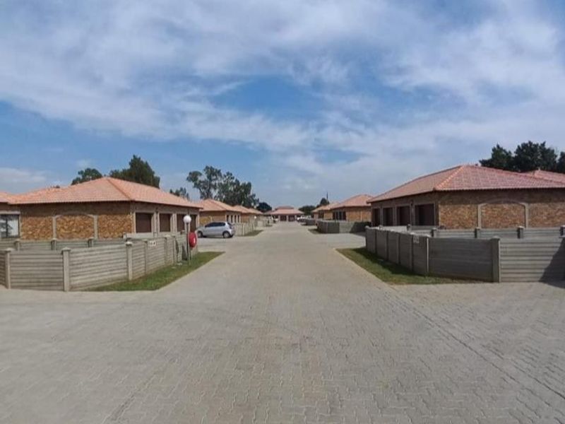 A view of a residential townhouse complex featuring paved driveways, facebrick facades, and precast concrete boundary walls.