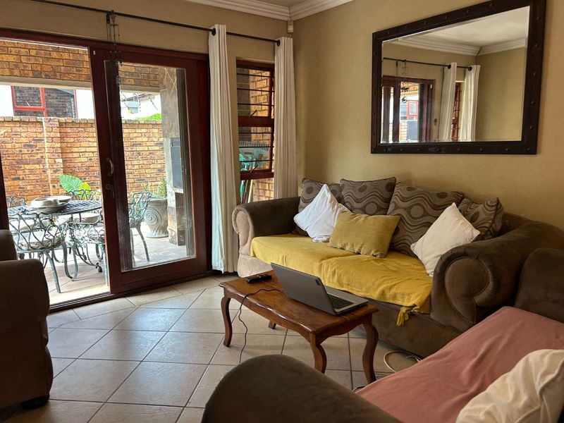 A living room featuring tiled flooring and a sliding glass door providing direct access to an outdoor patio area.
