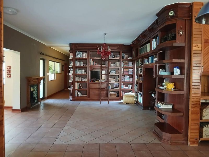 Spacious living area featuring extensive built-in wooden cabinetry, a fireplace, and tiled flooring, offering a classic and functional library-style layout.