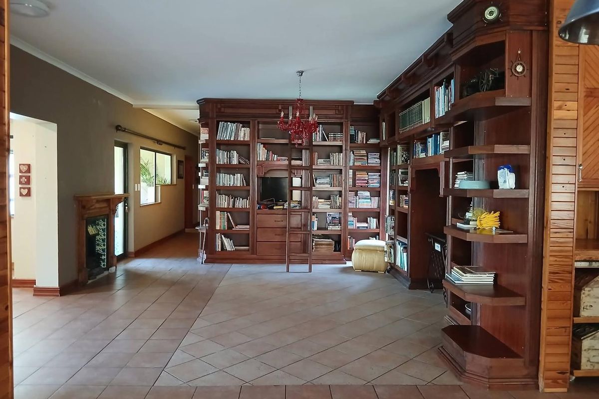 Spacious living area featuring extensive built-in wooden cabinetry, a fireplace, and tiled flooring, offering a classic and functional library-style layout.