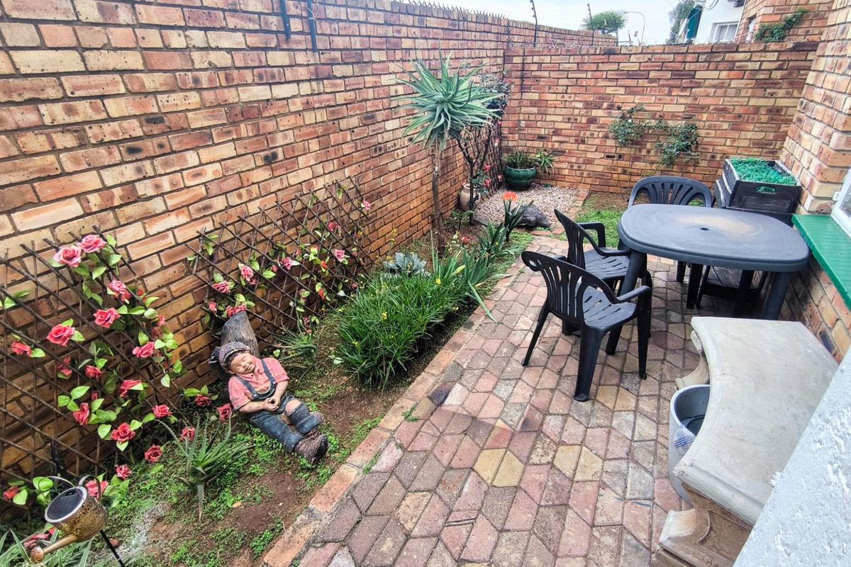 A private rear courtyard featuring a paved patio area enclosed by high brick boundary walls with integrated electric security fencing.