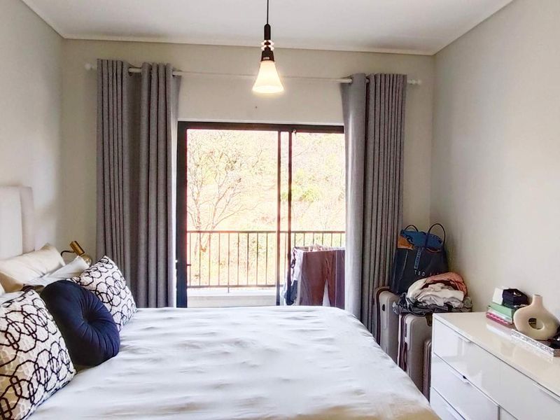 A well-lit bedroom featuring a large sliding glass door providing access to a private balcony and natural light.