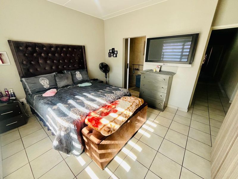 A bedroom featuring tiled flooring and direct access to an en-suite bathroom, providing a functional layout for a townhouse residence.