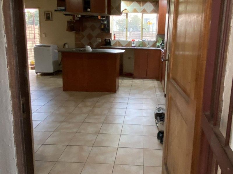 A dated kitchen featuring built-in wooden cabinetry, a central island, and tiled flooring, offering significant potential for a modern renovation.