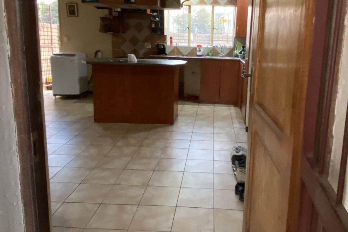 A dated kitchen featuring built-in wooden cabinetry, a central island, and tiled flooring, offering significant potential for a modern renovation.