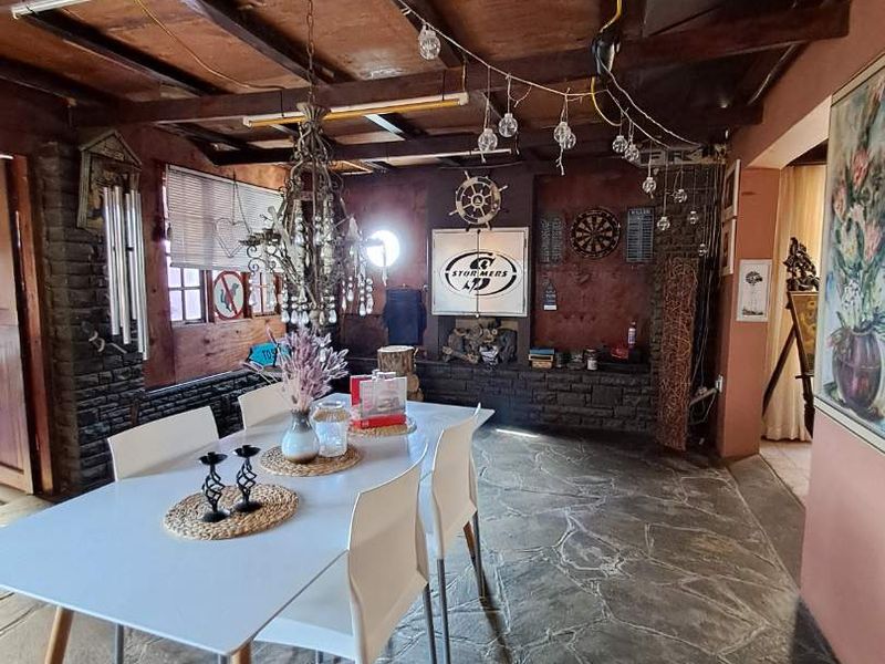 Dining area featuring exposed timber ceiling beams, stone tile flooring, and a stone feature wall with a built-in fireplace.