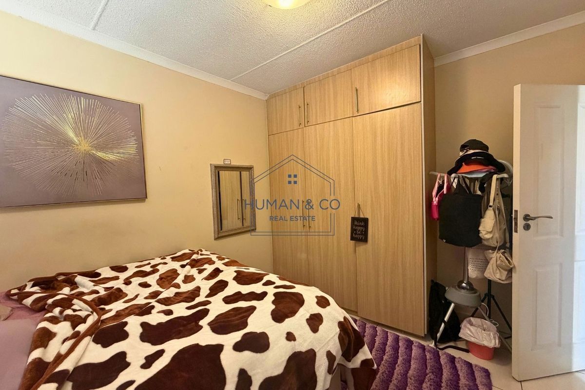 A bedroom featuring built-in wooden wardrobes, tiled flooring, and a central ceiling light fixture.
