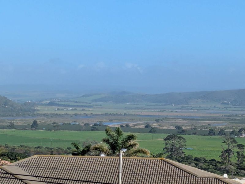 An elevated view overlooking a rural landscape with green fields and distant hills, captured from a property with a tiled roof.