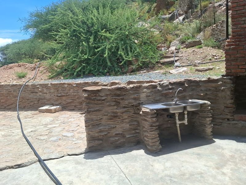 Outdoor patio area featuring a built-in braai and a stone-clad prep station with a double stainless steel sink.