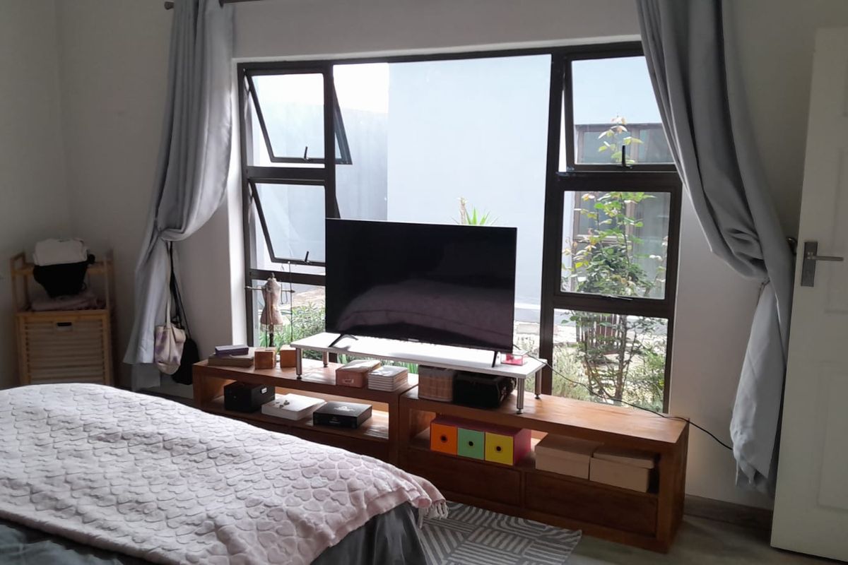 A bedroom featuring large aluminium-framed windows that provide natural light and a view of the exterior garden area.