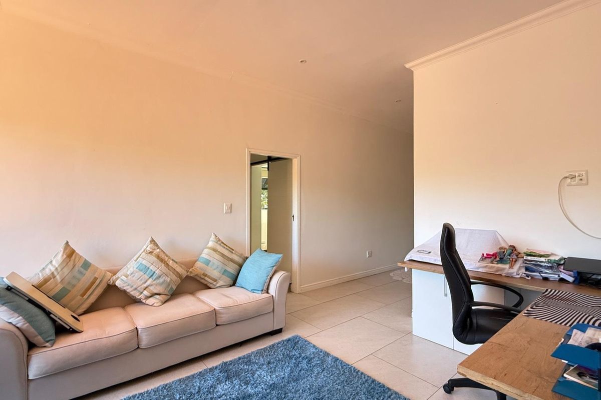 A multi-functional living space featuring tiled flooring, neutral walls, and a doorway leading to an adjacent room.