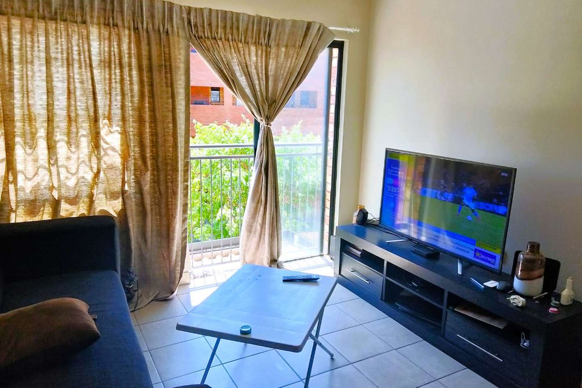 A living room featuring tiled flooring and a sliding glass door that opens onto a balcony, providing natural light.