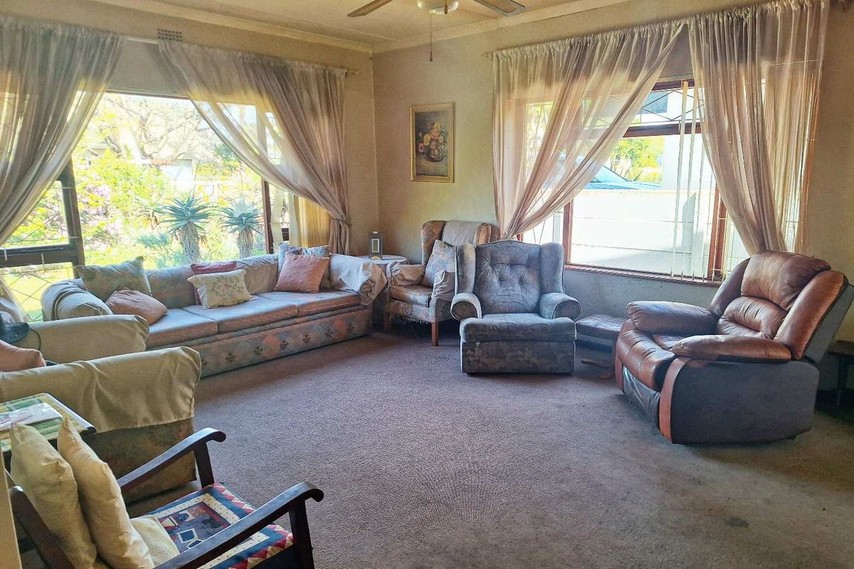 Spacious living room featuring large windows that provide ample natural light and a ceiling fan for climate control.