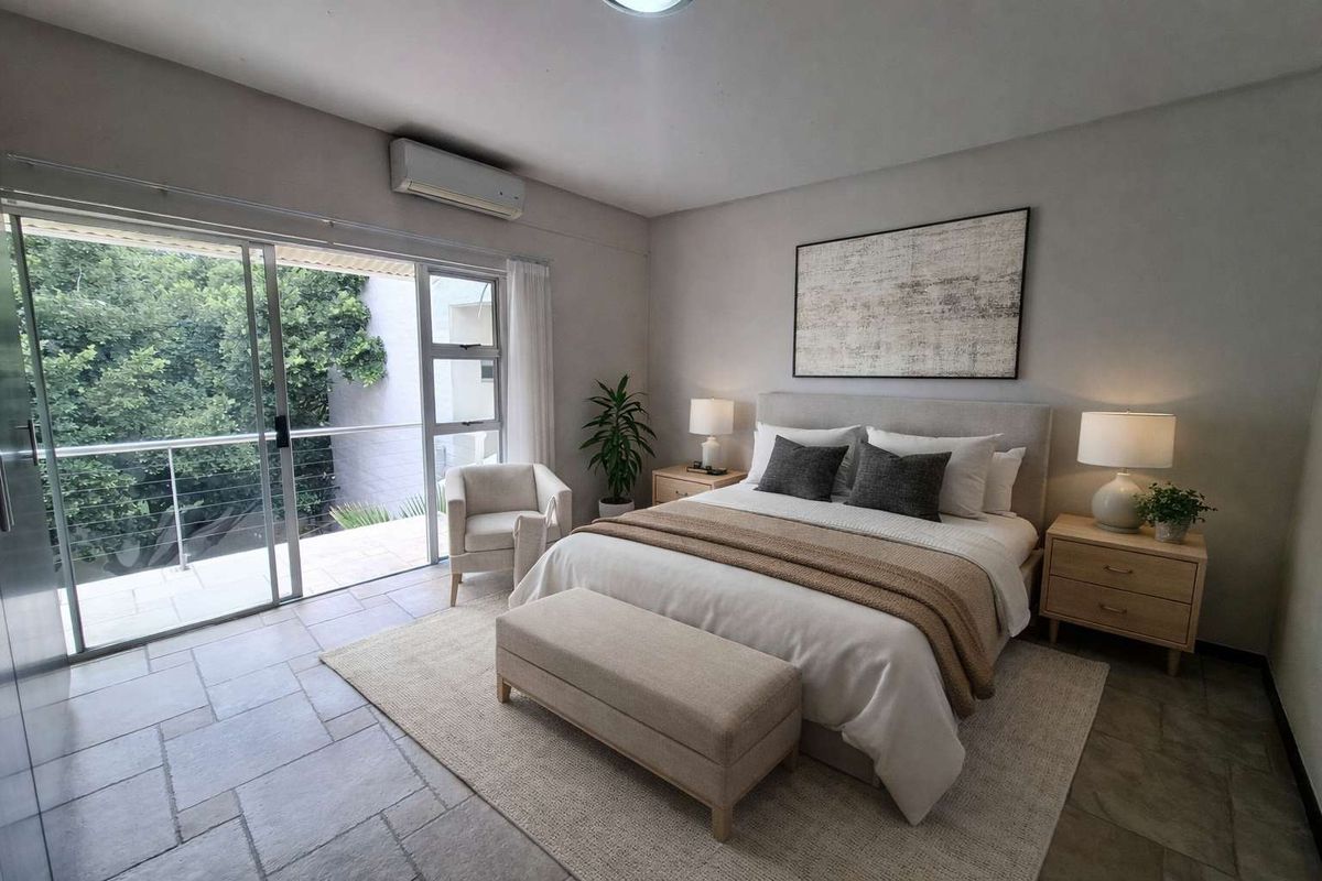 Spacious bedroom featuring tiled flooring, a wall-mounted air conditioning unit, and large sliding glass doors opening onto a private balcony.