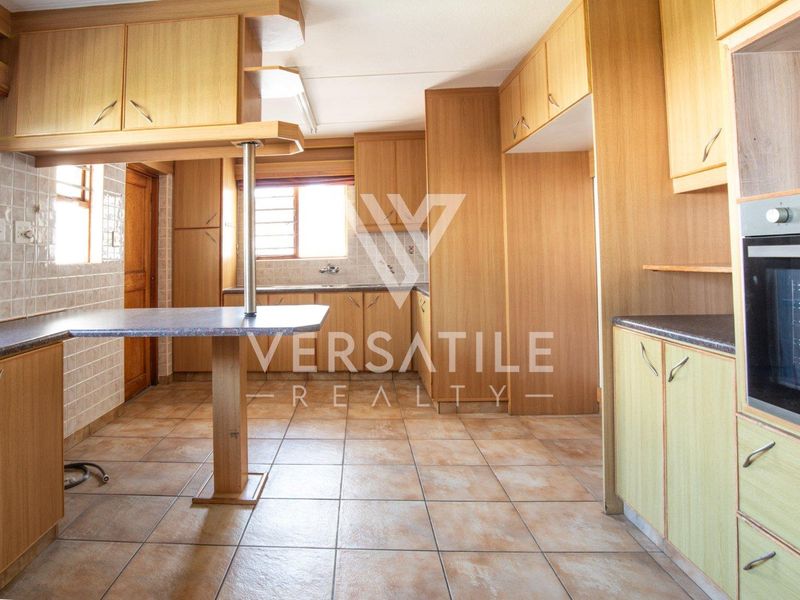 A functional kitchen featuring wood-look cabinetry, tiled flooring, a built-in oven, and a breakfast bar, offering a clean and practical layout.