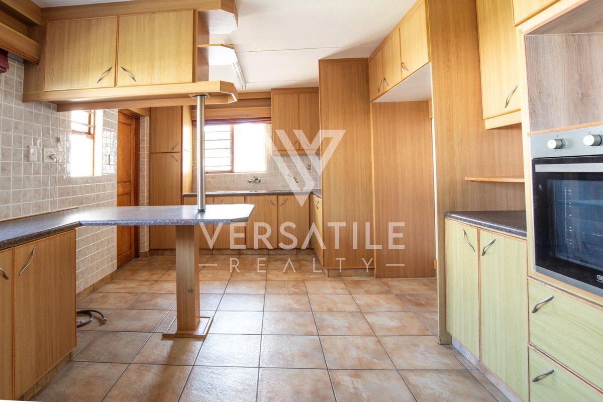 A functional kitchen featuring wood-look cabinetry, tiled flooring, a built-in oven, and a breakfast bar, offering a clean and practical layout.