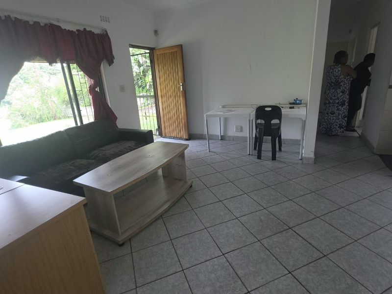 A living area featuring tiled flooring and a sliding door with security gate, providing access to the exterior.