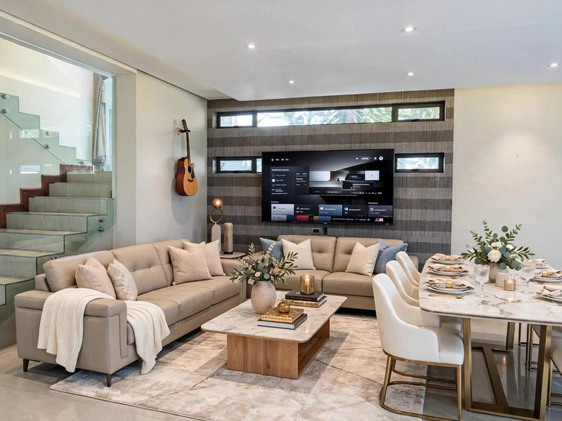 Modern open-plan living and dining area featuring a striking glass-railed staircase, contemporary feature wall, and high-quality tiled flooring throughout.