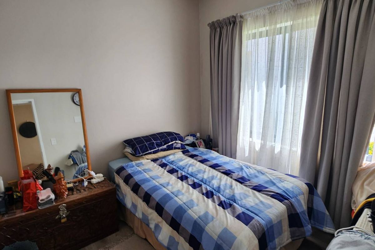 A standard bedroom featuring a window with curtain tracks and neutral wall finishes.