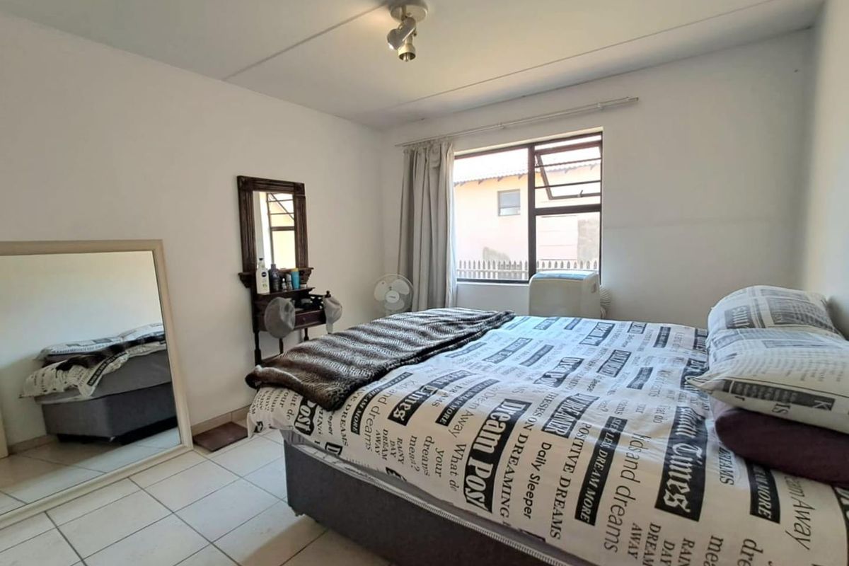 A functional bedroom featuring tiled flooring, a large window for natural light, and a standard ceiling light fixture.