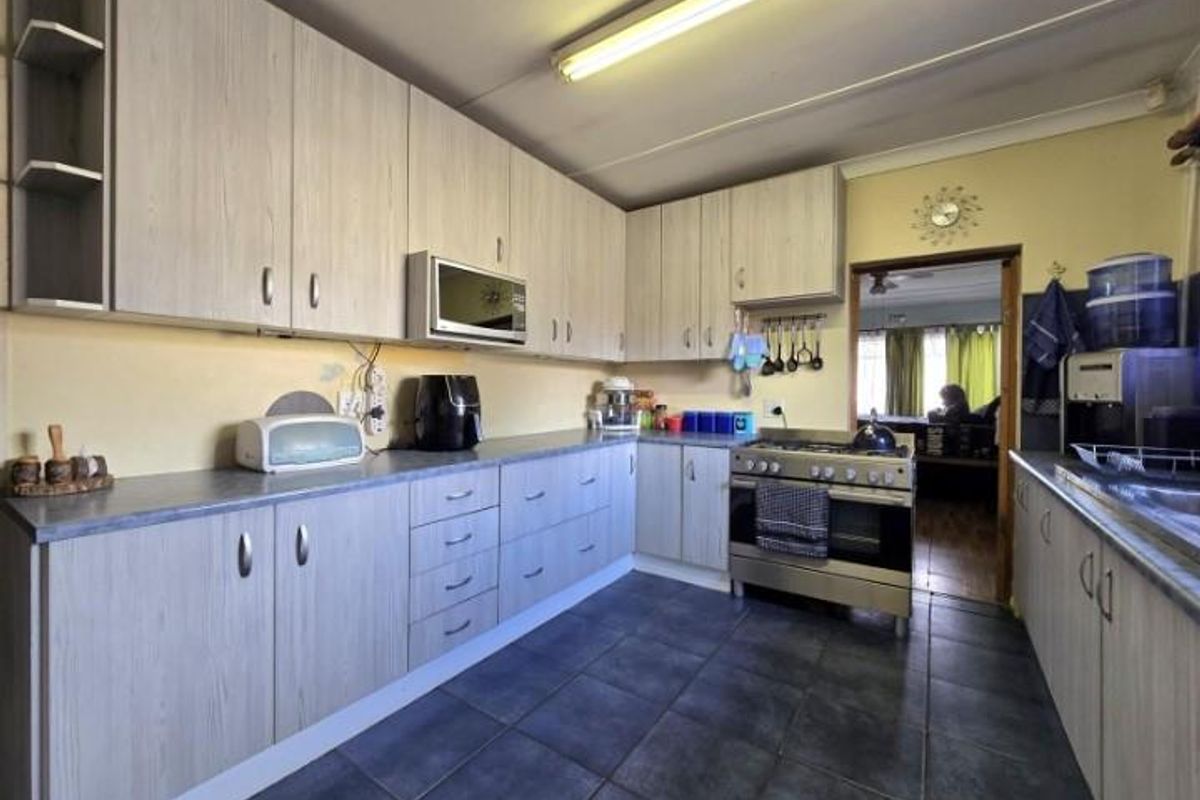 Functional kitchen featuring light wood-grain cabinetry, laminate countertops, tiled flooring, and a freestanding gas stove with an integrated microwave.