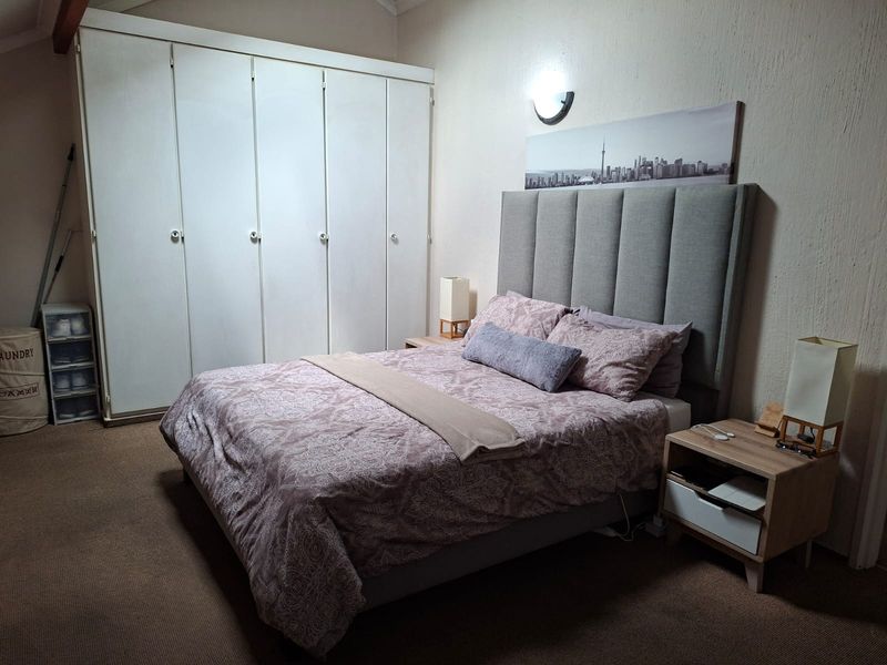 A bedroom featuring built-in cupboards and a wall-mounted light fixture, providing functional storage and lighting within the space.