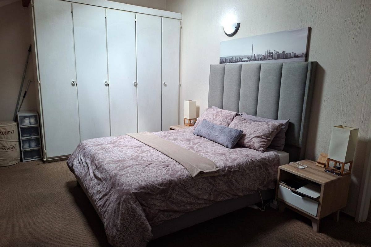 A bedroom featuring built-in cupboards and a wall-mounted light fixture, providing functional storage and lighting within the space.