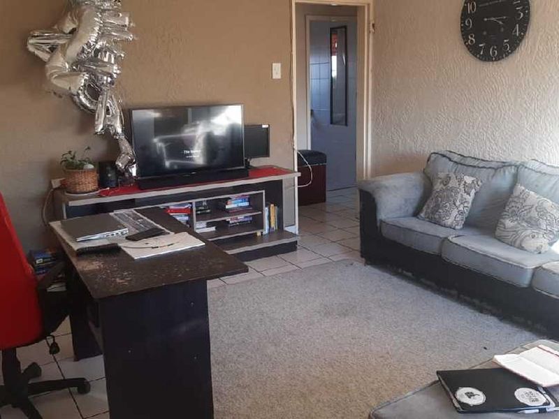 A living room area featuring tiled flooring and textured walls, offering a functional space that could benefit from cosmetic updates and modern finishes.