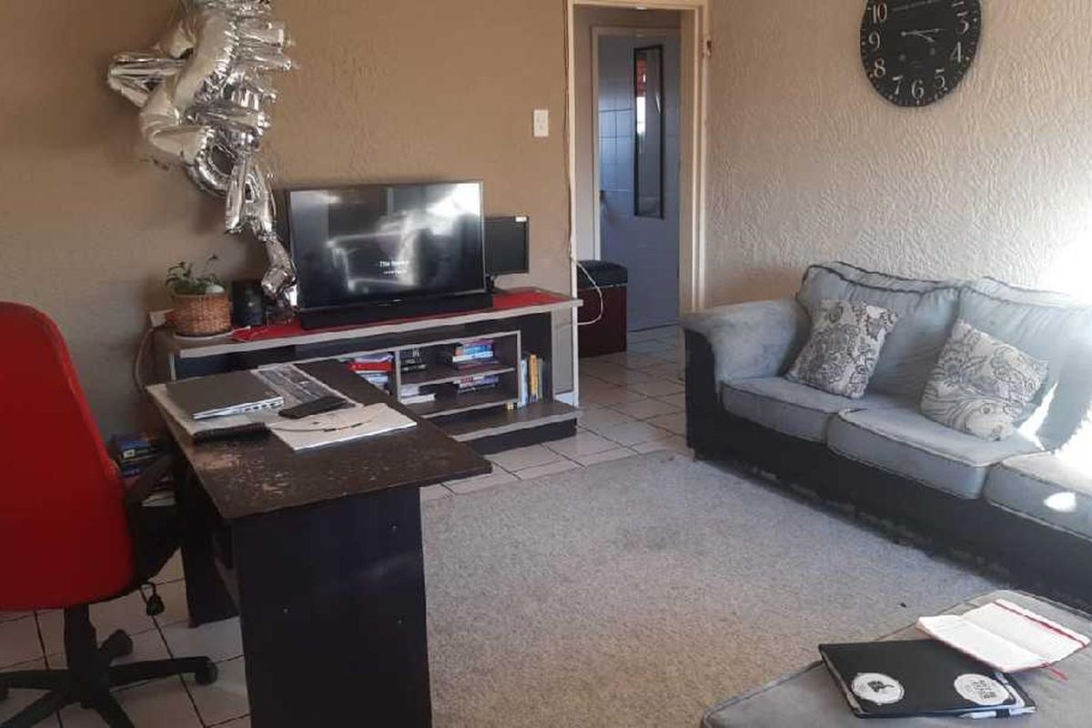 A living room area featuring tiled flooring and textured walls, offering a functional space that could benefit from cosmetic updates and modern finishes.