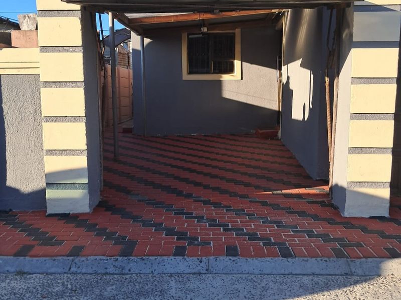 A paved, open-fronted garage structure featuring a concrete facade and a window with security bars.