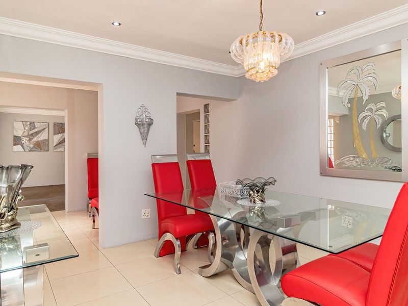 A well-maintained dining room featuring neutral wall tones, tiled flooring, crown molding, and recessed ceiling lighting, creating a bright and inviting atmosphere.