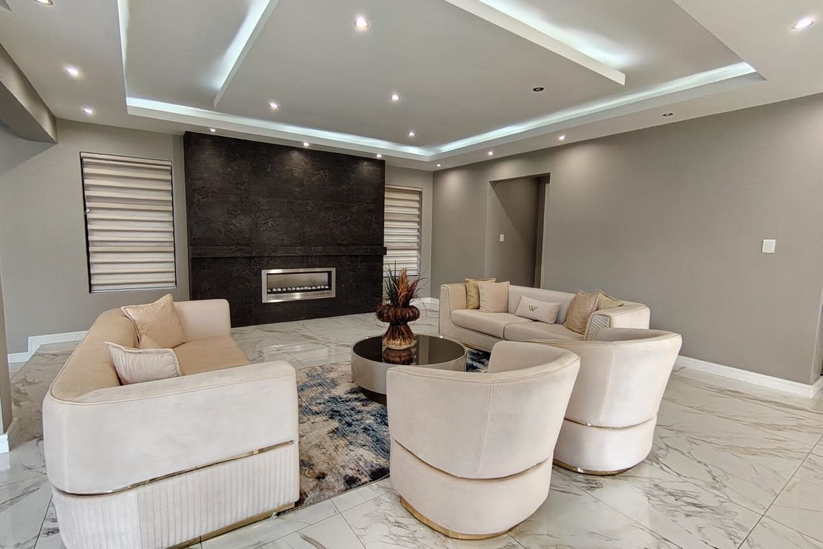 Modern living room featuring a striking dark feature wall with a built-in fireplace, elegant marble-look flooring, and a sophisticated recessed ceiling with ambient lighting.
