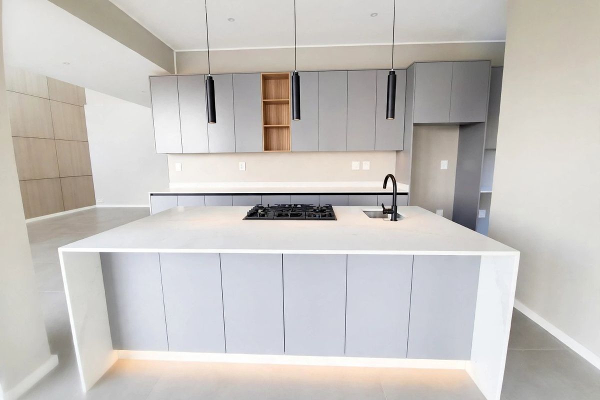 Modern open-plan kitchen featuring a central island with a gas hob, undermount sink, sleek grey cabinetry, and integrated under-cabinet lighting.