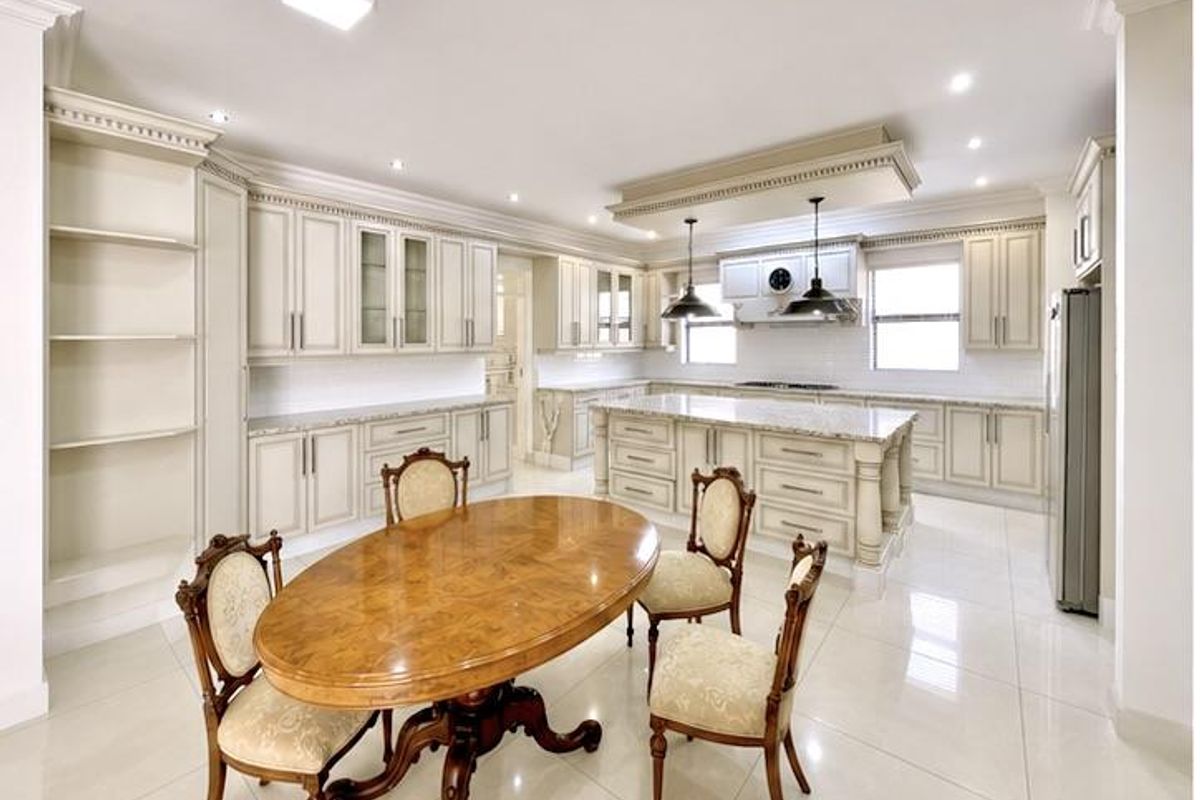 Spacious, well-appointed kitchen featuring extensive custom cabinetry, a large central island with stone countertops, and high-quality finishes throughout.