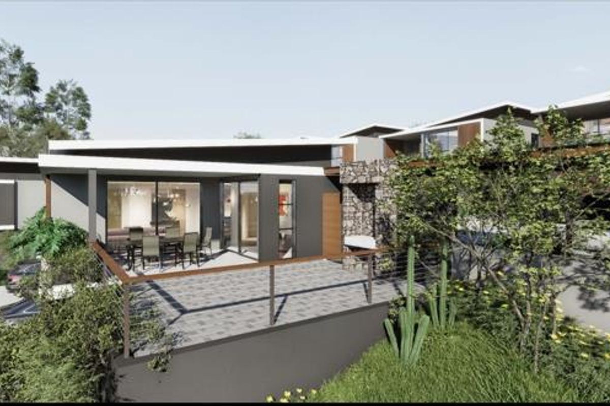 A modern rear exterior view featuring a paved patio, stone-clad chimney, and expansive sliding glass doors, showcasing contemporary architectural design.