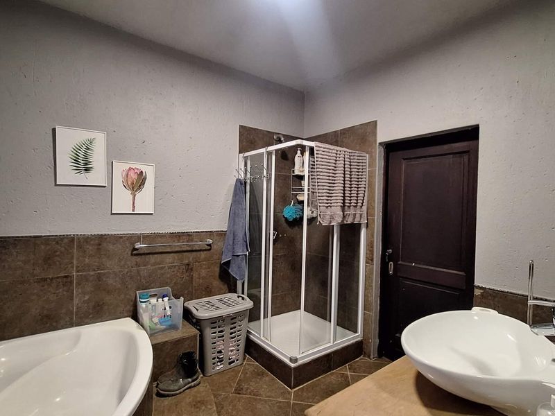 A functional bathroom featuring a corner bathtub, a separate shower enclosure, and a modern vessel sink with tiled finishes.