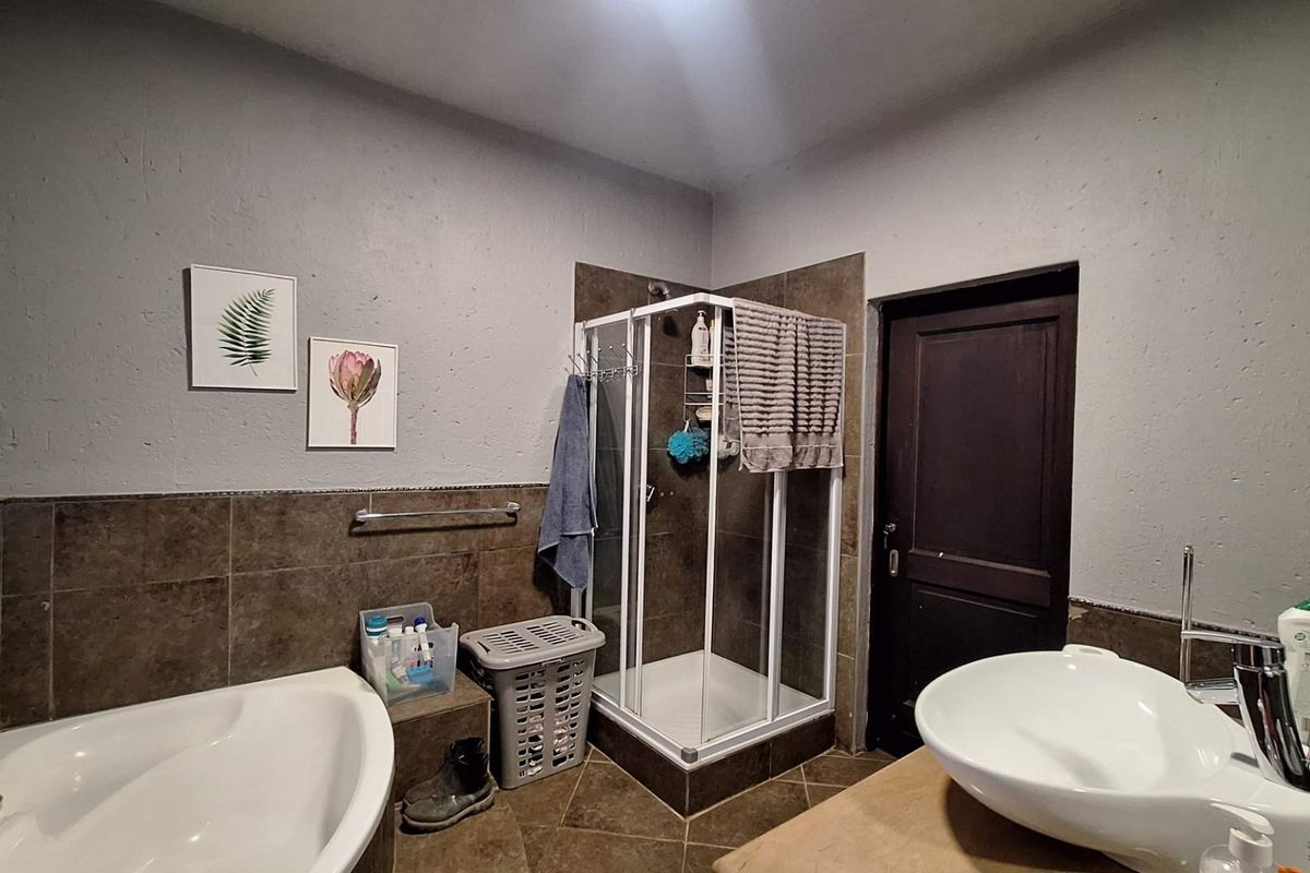 A functional bathroom featuring a corner bathtub, a separate shower enclosure, and a modern vessel sink with tiled finishes.