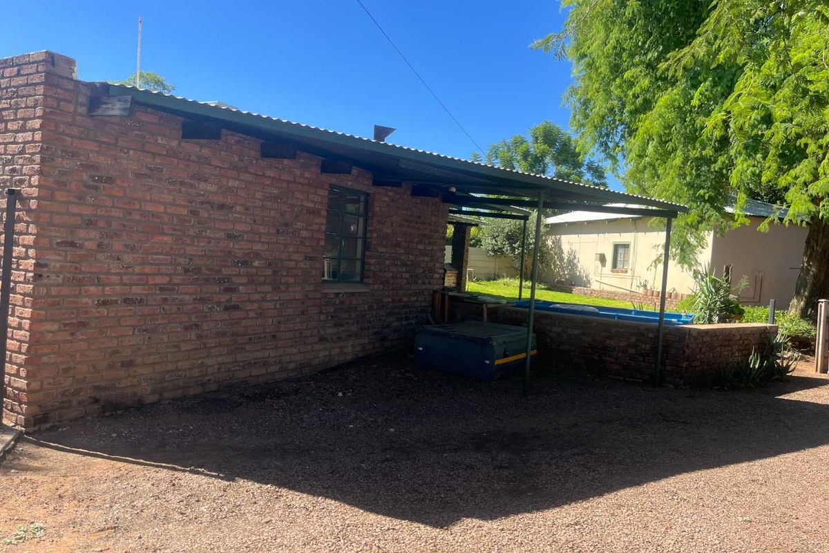 A view of the rear exterior of the house featuring exposed brick walls, a corrugated metal roof, and a covered outdoor area.