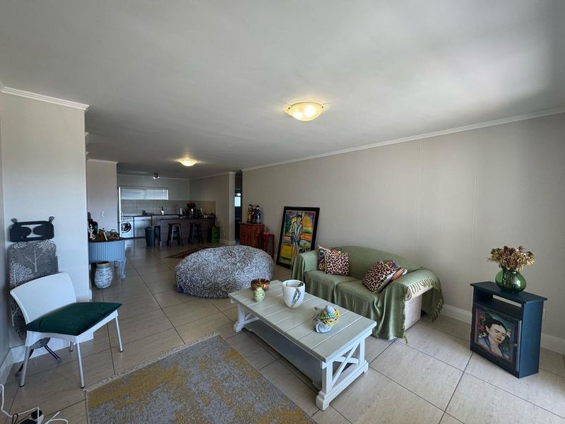 Open-plan living area featuring tiled flooring and a functional kitchen space with built-in cabinetry and appliances.
