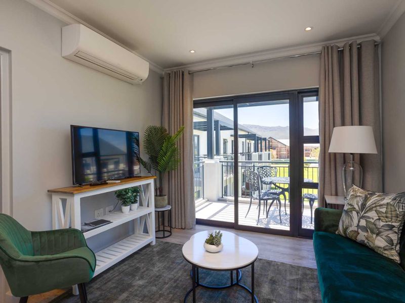 A well-maintained living room featuring laminate flooring, recessed lighting, and a split-system air conditioner, with direct access to a private balcony.