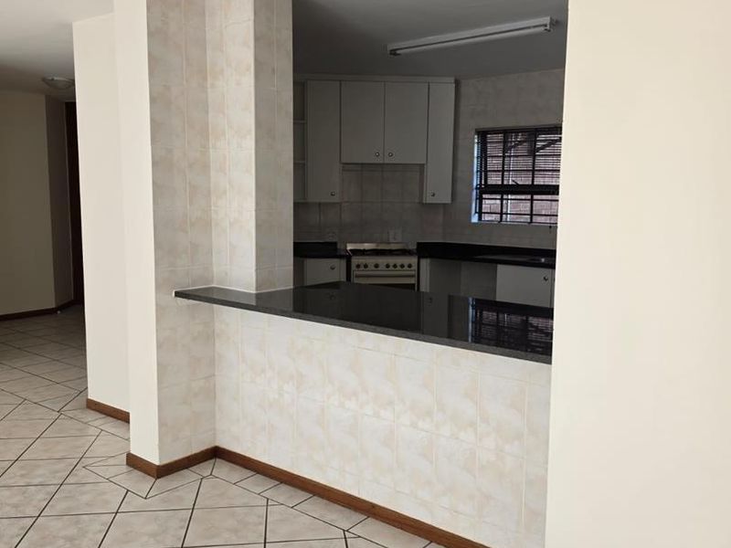 A functional kitchen featuring granite countertops, a breakfast bar, and tiled finishes, offering a clean and practical layout for daily use.
