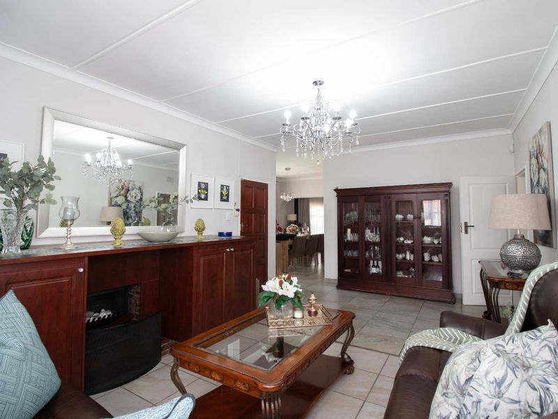 A well-maintained living room featuring a built-in fireplace, tiled flooring, and classic ceiling detailing, creating a warm and inviting atmosphere.