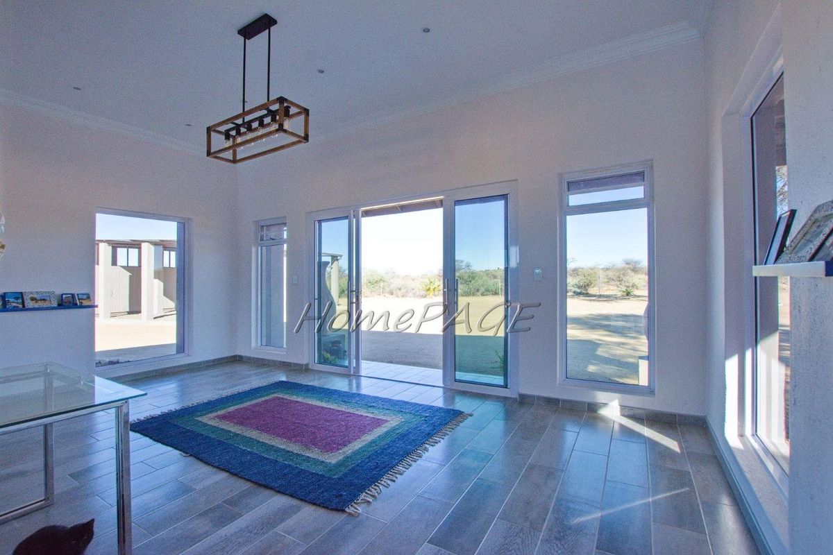 Bright and spacious living area featuring large sliding glass doors, tiled flooring, and modern recessed lighting, offering seamless access to the outdoor space.