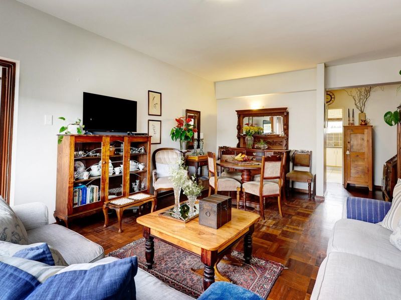 Open-plan living and dining area featuring classic parquet flooring and direct access to an outdoor space through a sliding glass door.