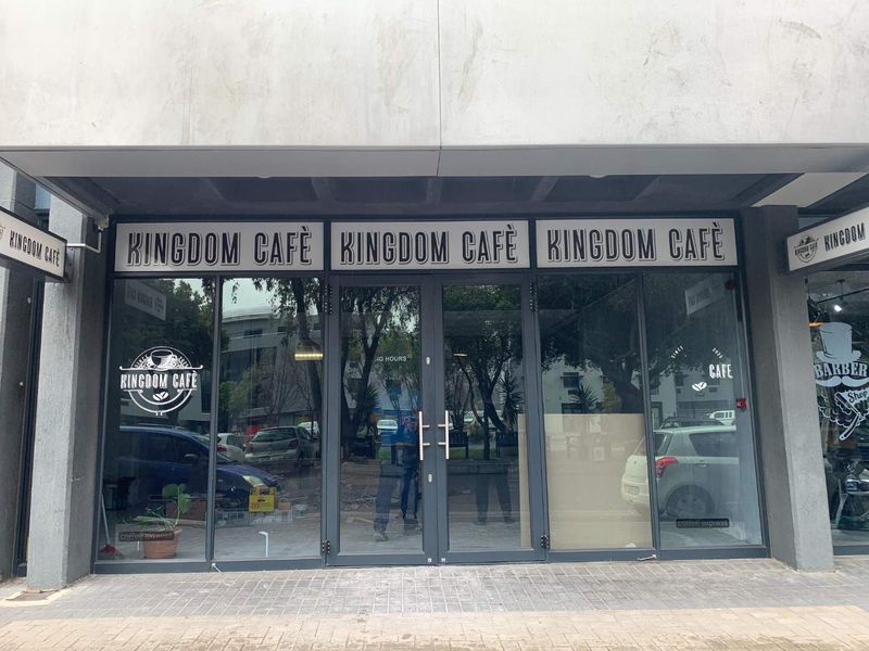Front facade of a retail cafe unit featuring a modern glass storefront, double entry doors, and clear signage.