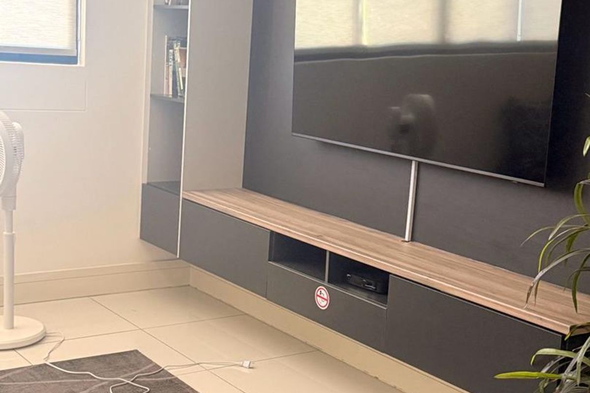 A modern living room featuring a sleek, dark-toned floating media console with integrated shelving and neutral tiled flooring.