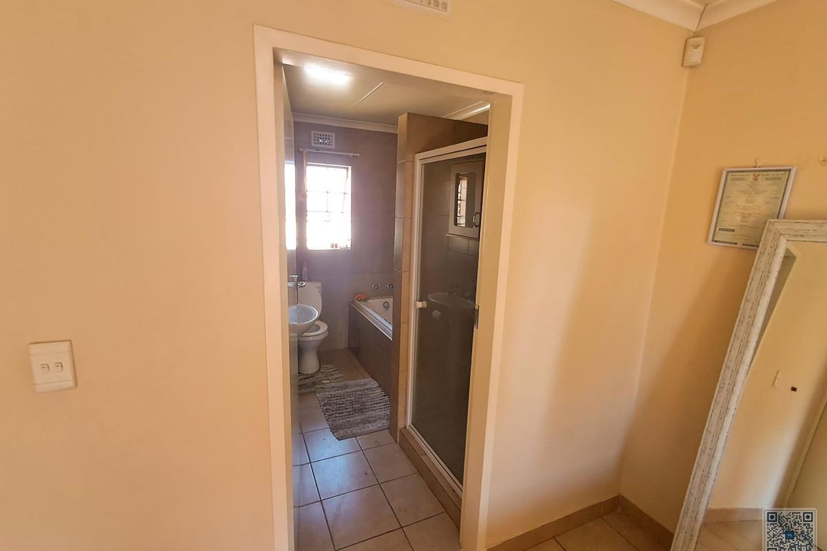 A functional bathroom featuring a shower enclosure, bathtub, and pedestal basin with tiled flooring and neutral wall finishes.