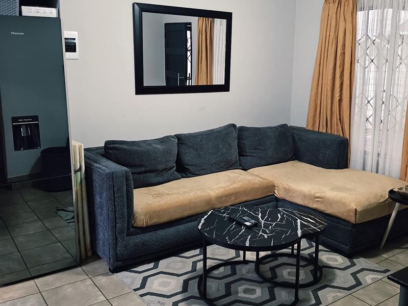 A living room area featuring tiled flooring and a security gate at the window, providing a functional and secure living space.